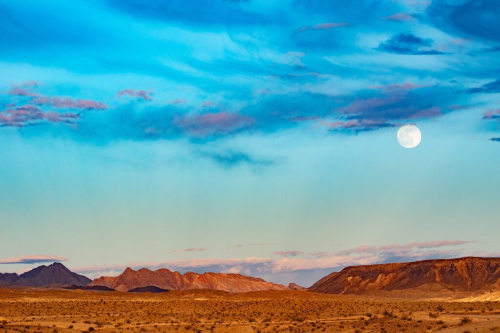 Barren arid mountain desert landscape with full moon blue hour near Lake Mead by Las Vegas, Nevada, NV, US America, USA.