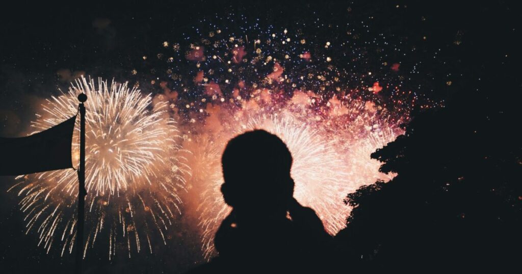 Silhouette of people watching fireworks at night.