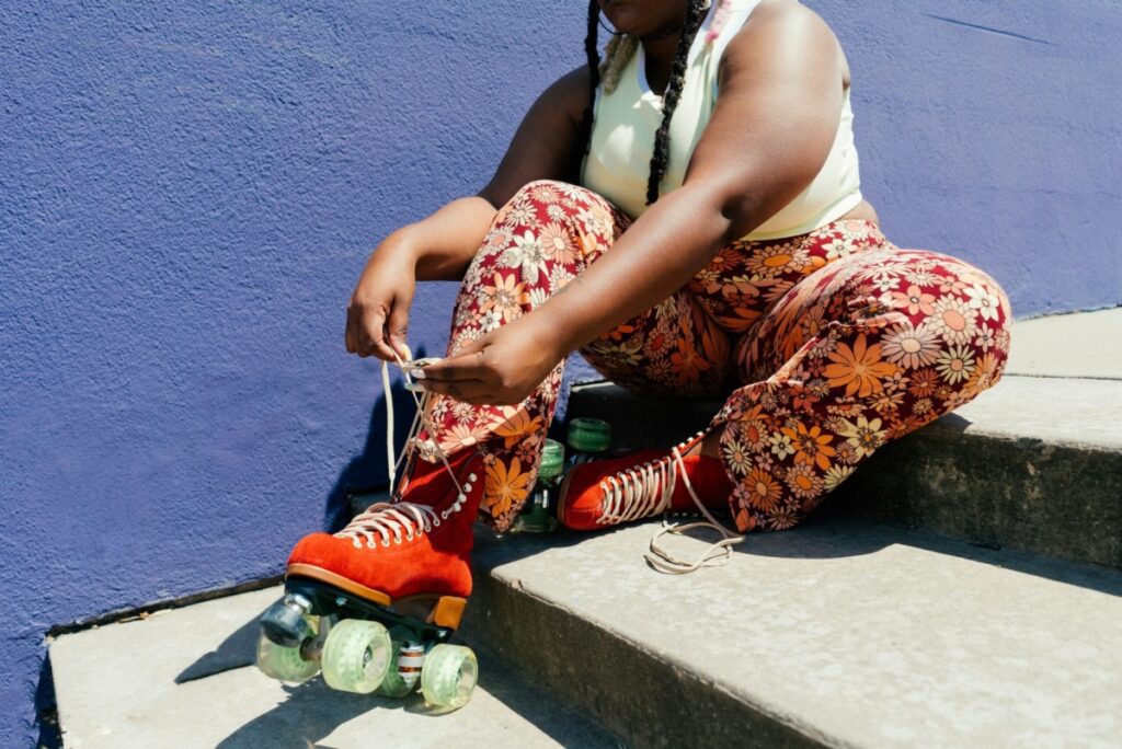 Woman lacing up roller skates while sitting on a step.