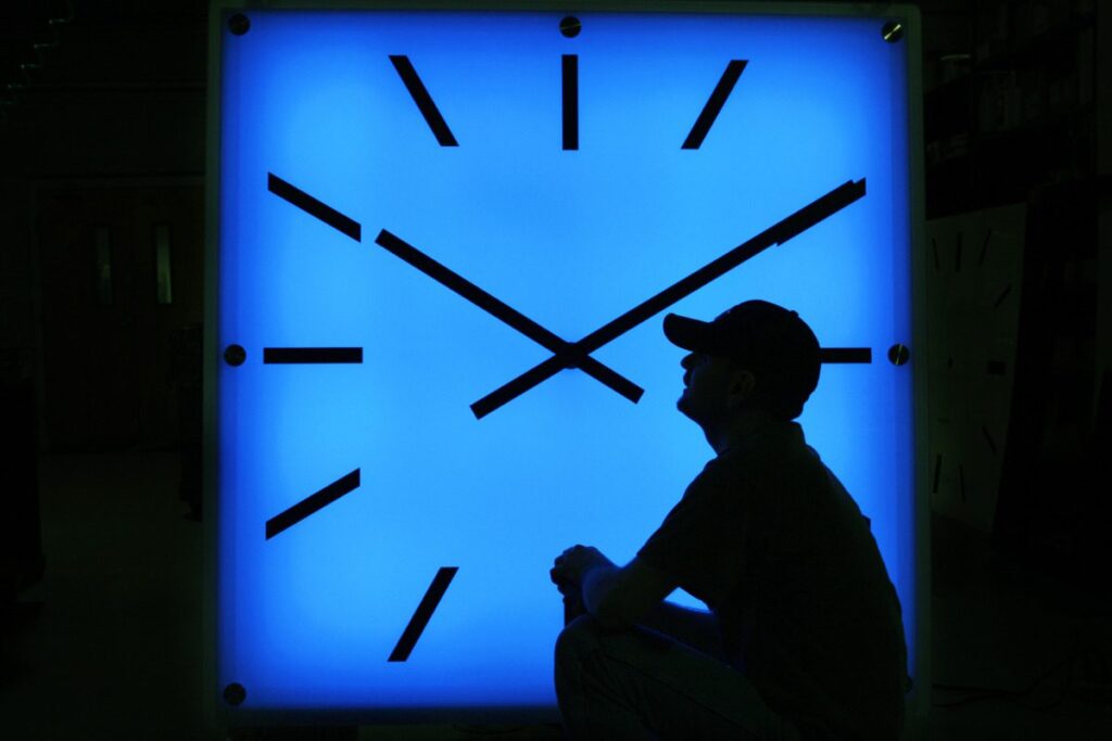 FILE - In this Oct. 30, 2008, file photo, an Electric Time Company employee adjusts the color on a clock at the plant in Medfield, Mass., days before the switch to standard time. (AP Photo/Elise Amendola, File)