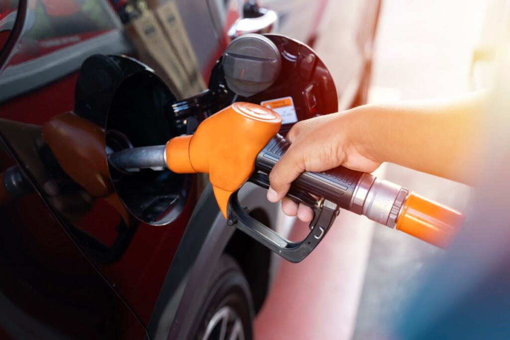 hand filling up gas tank at station.