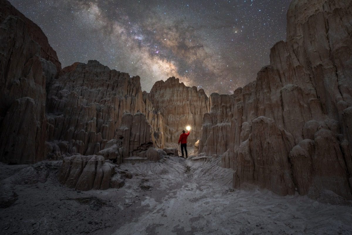 a person holds up a light to further illuminate the night sky