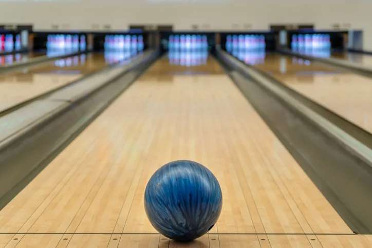 Blue bowling ball on the track in the bowling center