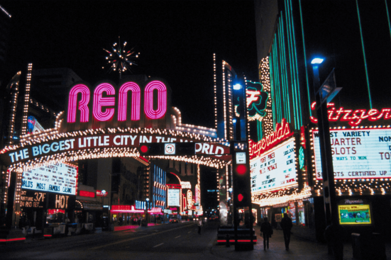 The Reno welcome sign surrounded by twinkling casino lights at night.