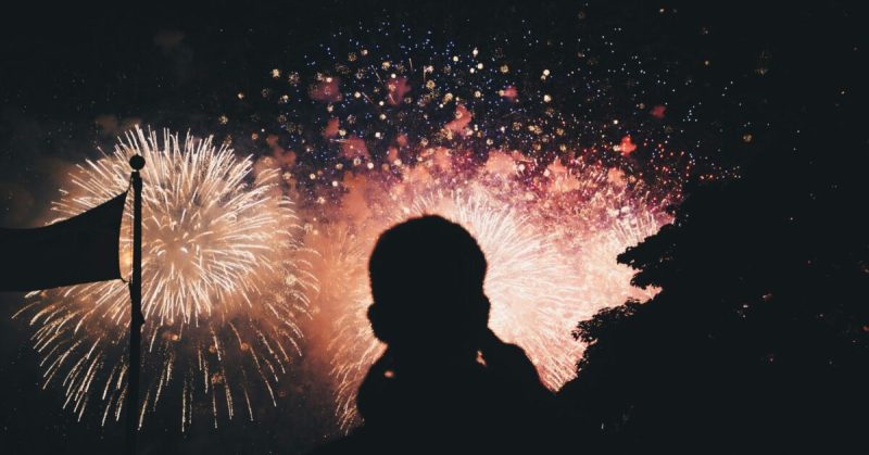 Silhouette of people watching fireworks at night.