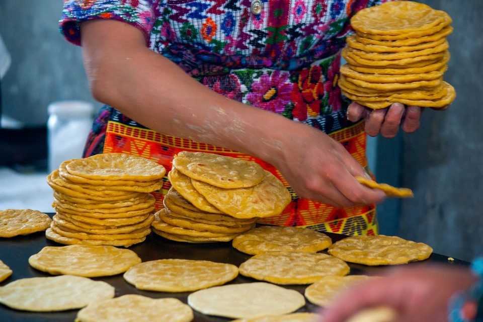 A woman making fresh tortillas in a Hispanic grocery store.