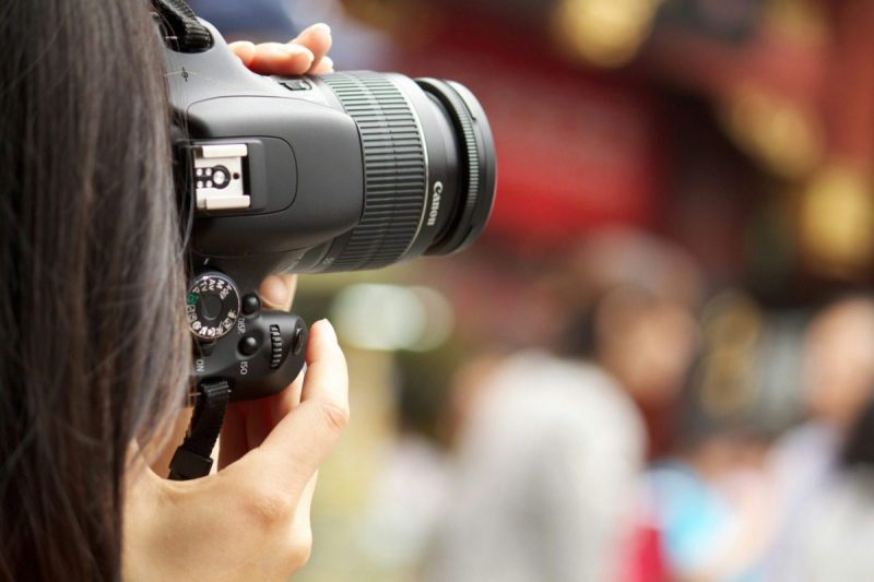 Young woman holding a camera up to her face to take a photo.