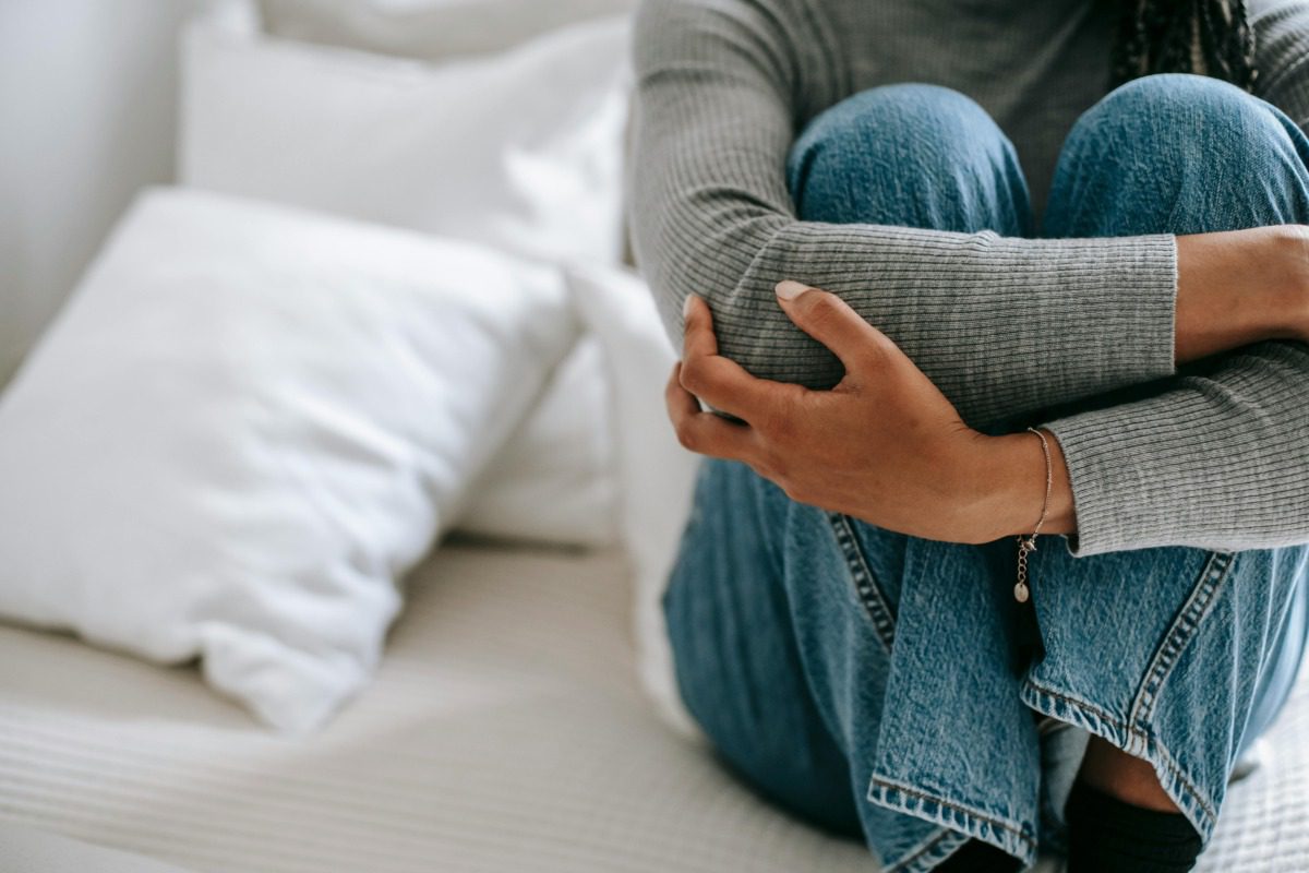 young woman sitting holding her knees to her chest
