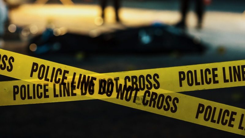 yellow crime tape reading ""police line do not cross" criss crosses across a crime scene