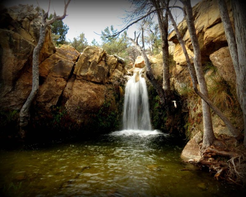 a small waterfall cascades into a body of water surrounded by rocks
