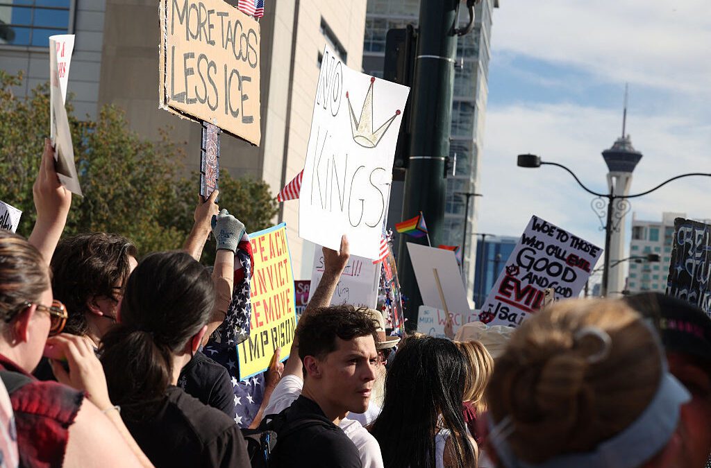 People hold signs as they protest against the Trump administration during the 