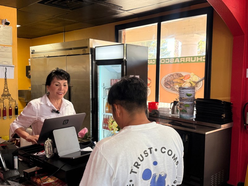 A customer orders food at the cash register of a restaurant.
